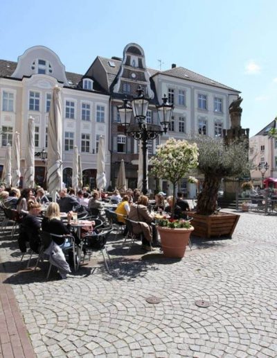 Das Foto zeigt den Altmarkt im Herzen der Moerser Innenstadt. Die verschiedenen Gastronomieangebote rund um den Platz laden zum Verweilen in der Altstadt ein.