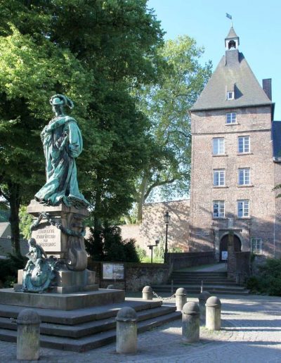 Das Foto zeigt das Moerser Schloss mit dem Grafschafter Museum. Vor dem Schloss steht die Statue von Luise Henriette von Oranien.